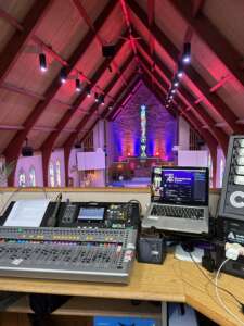 View of a church sanctuary, from a tech booth containing a light or sound board, laptop, etc.